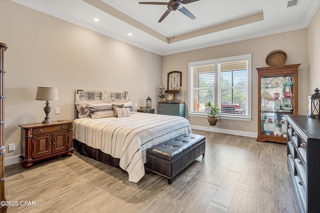 bedroom featuring light wood-type flooring, ceiling fan, baseboards, and a raised ceiling