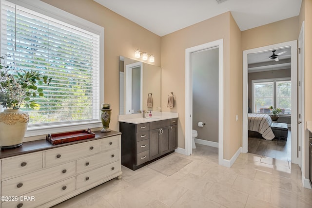 full bath featuring connected bathroom, toilet, vanity, baseboards, and a ceiling fan