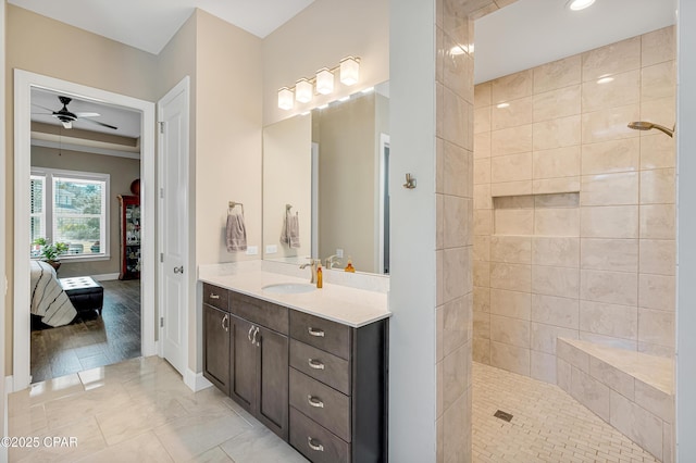 ensuite bathroom featuring a walk in shower, ceiling fan, connected bathroom, vanity, and baseboards