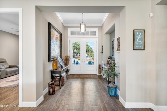 foyer entrance with crown molding, baseboards, and wood finished floors