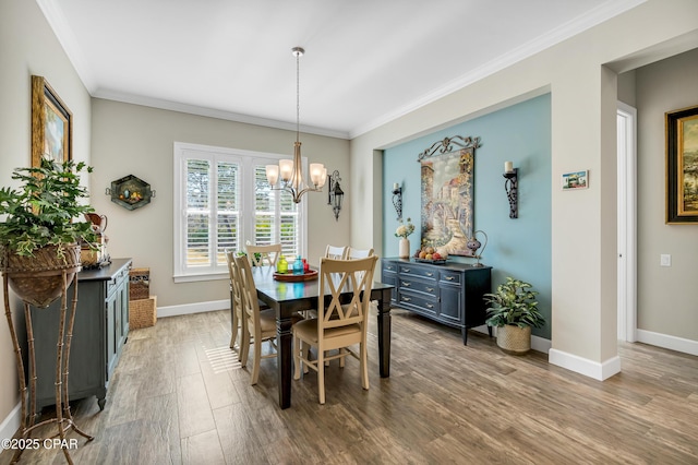 dining area with a notable chandelier, crown molding, baseboards, and wood finished floors