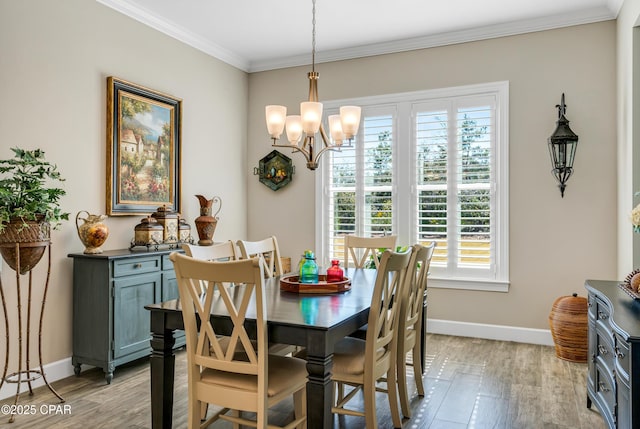 dining area featuring light wood-style floors, crown molding, baseboards, and an inviting chandelier