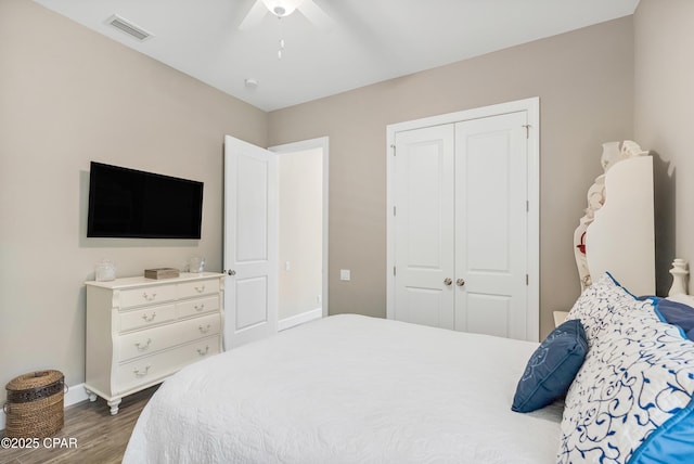 bedroom featuring wood finished floors, a ceiling fan, visible vents, baseboards, and a closet