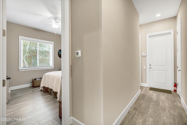 hallway featuring baseboards, recessed lighting, and light wood-style floors