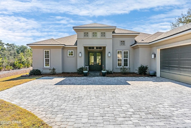 view of front of home with a garage, french doors, and stucco siding