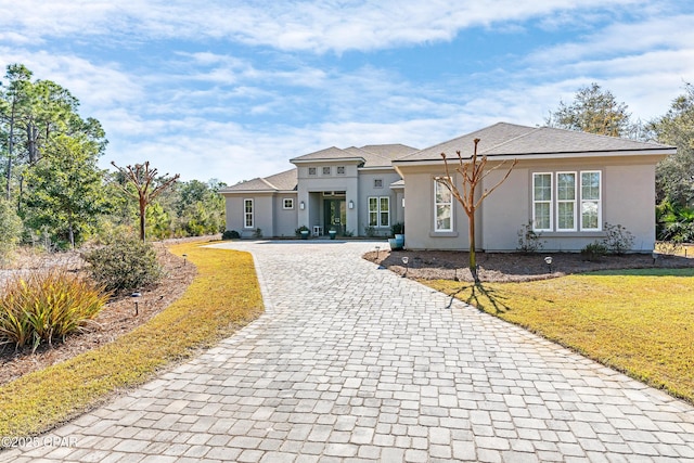 view of front of property with a front lawn, decorative driveway, and stucco siding