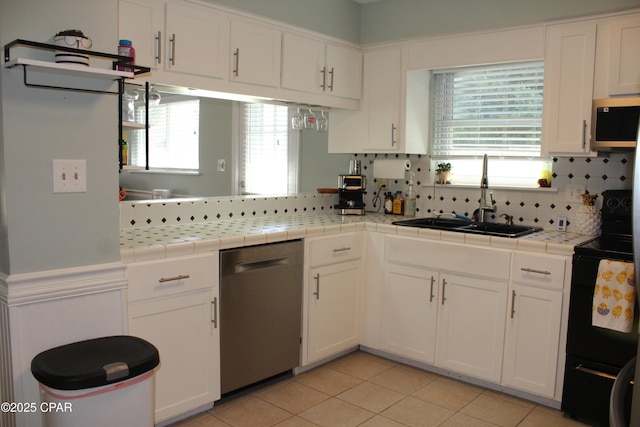 kitchen with tile countertops, light tile patterned flooring, stainless steel appliances, a sink, and white cabinetry