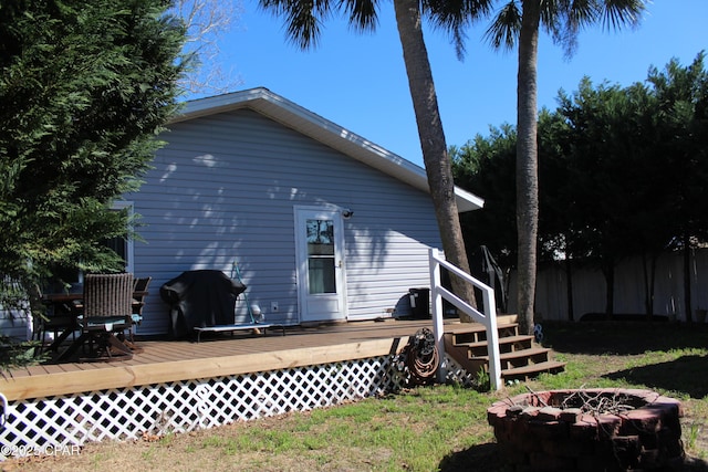 back of house with a fire pit, fence, and a wooden deck