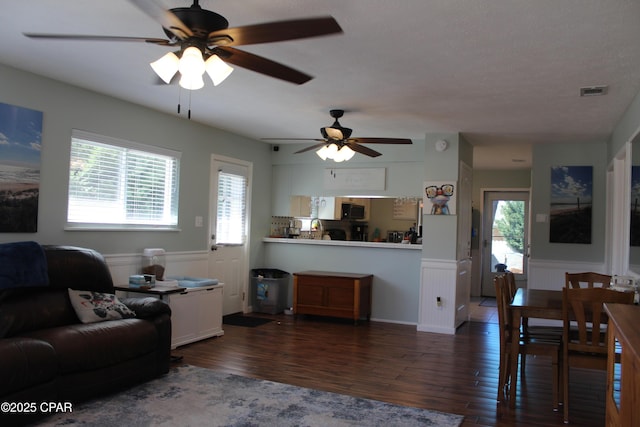 living area featuring wainscoting, wood finished floors, and a healthy amount of sunlight