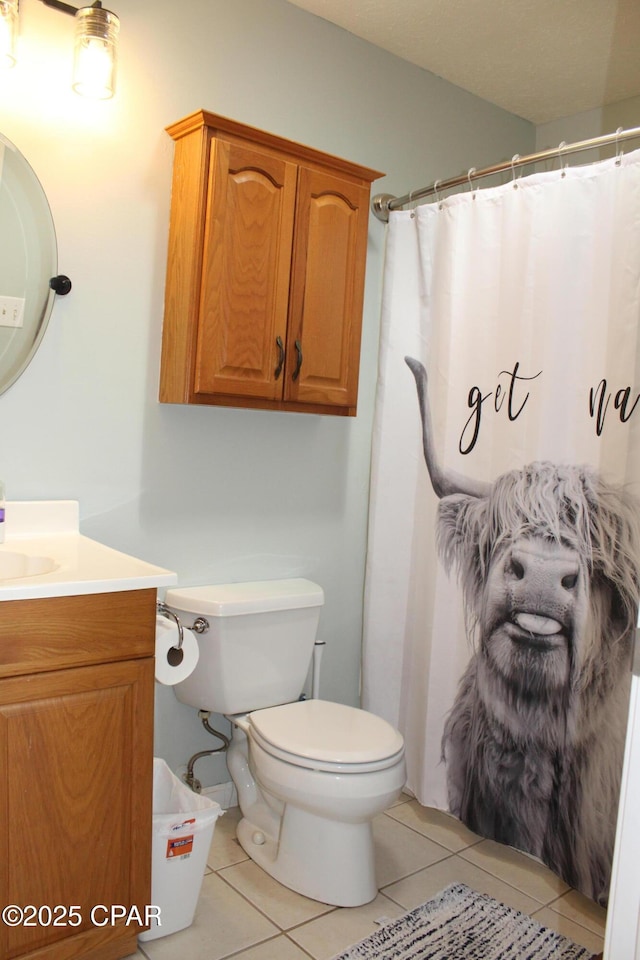 bathroom with toilet, curtained shower, vanity, and tile patterned floors