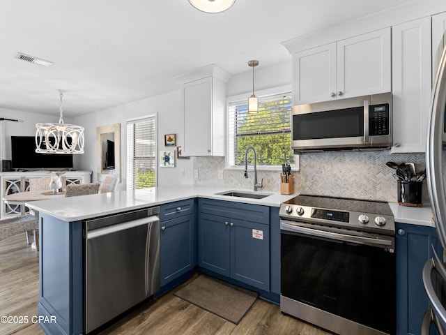3799 E County Highway 30a Unit B12, Santa Rosa Beach, FL 32459 - kitchen featuring appliances with stainless steel finishes, blue cabinetry, a peninsula, white cabinetry, and wood finished floors