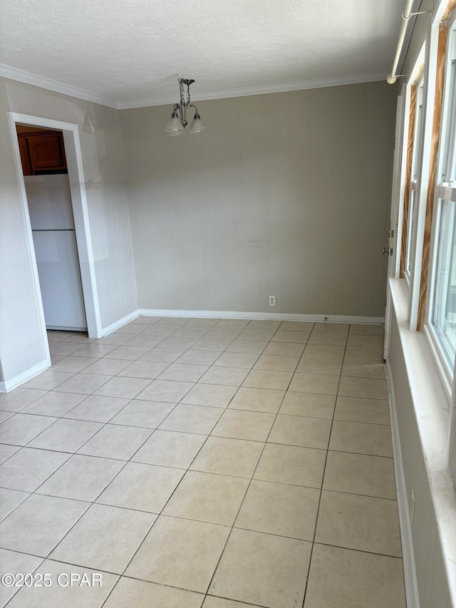 spare room with a notable chandelier, crown molding, light tile patterned floors, a textured ceiling, and baseboards