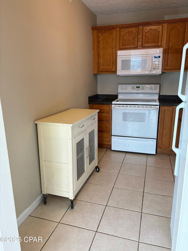 kitchen with white appliances, brown cabinets, baseboards, and light tile patterned flooring