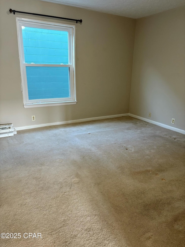 carpeted spare room with a textured ceiling and baseboards