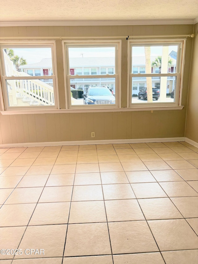 empty room with baseboards, a textured ceiling, and tile patterned floors