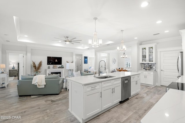 kitchen with decorative light fixtures, white cabinetry, an island with sink, sink, and stainless steel dishwasher