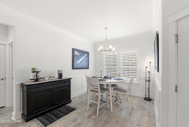 dining area with an inviting chandelier, ornamental molding, and light wood-type flooring