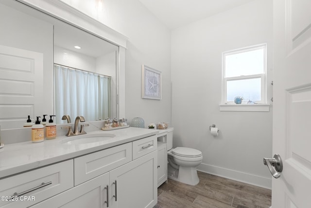 bathroom featuring hardwood / wood-style flooring, vanity, toilet, and curtained shower