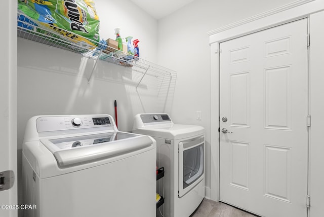 laundry room with independent washer and dryer and light wood-type flooring