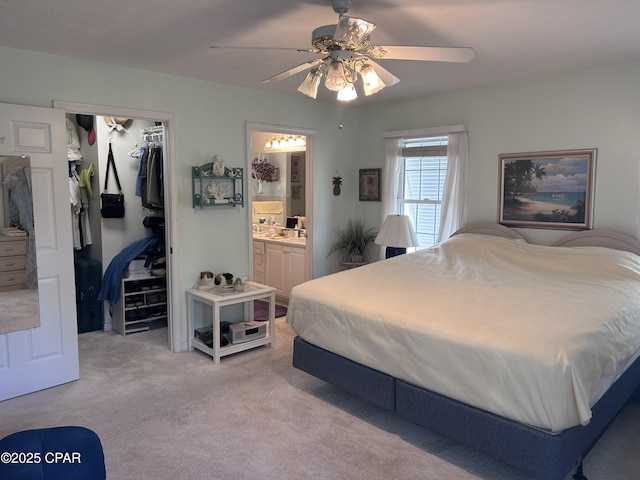 bedroom featuring a closet, light carpet, a spacious closet, a ceiling fan, and connected bathroom