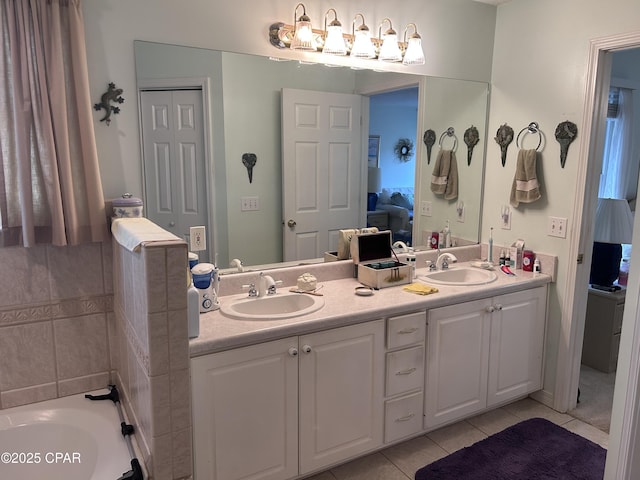 ensuite bathroom with tile patterned floors, double vanity, a bathtub, and a sink