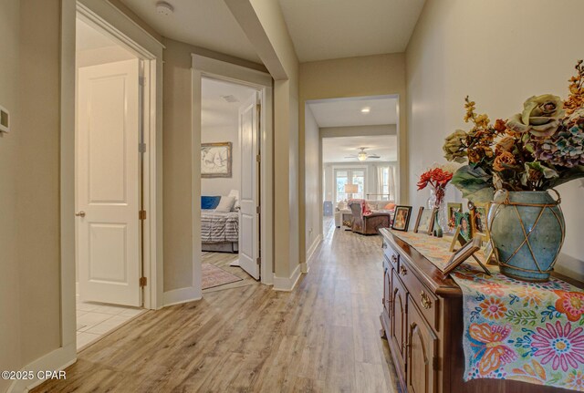 living area featuring light wood-style floors, visible vents, a wealth of natural light, and ceiling fan with notable chandelier