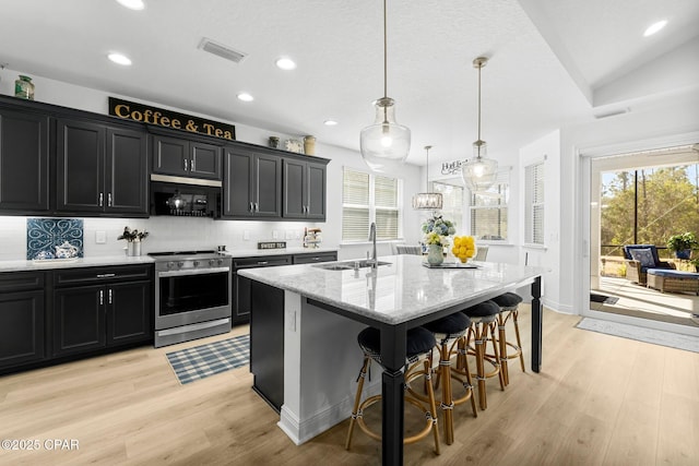 kitchen featuring an island with sink, sink, stainless steel range, and decorative light fixtures