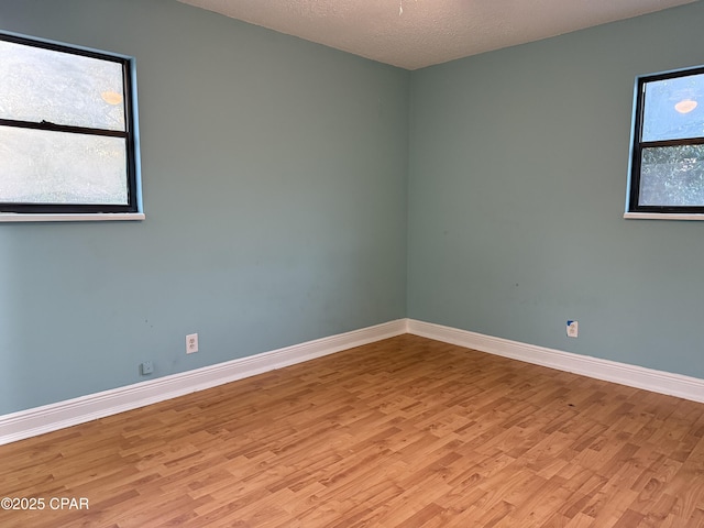 empty room with light hardwood / wood-style flooring and a textured ceiling