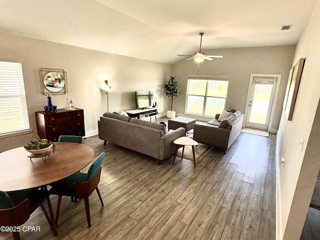 living area featuring a ceiling fan, visible vents, vaulted ceiling, and wood finished floors