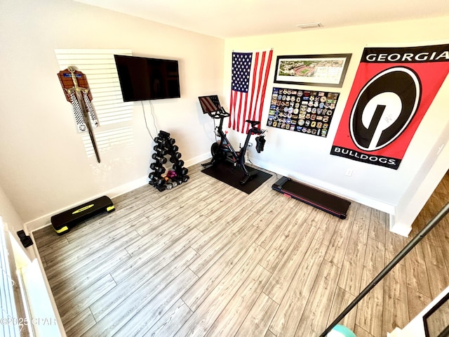 exercise room with visible vents, baseboards, and wood finished floors