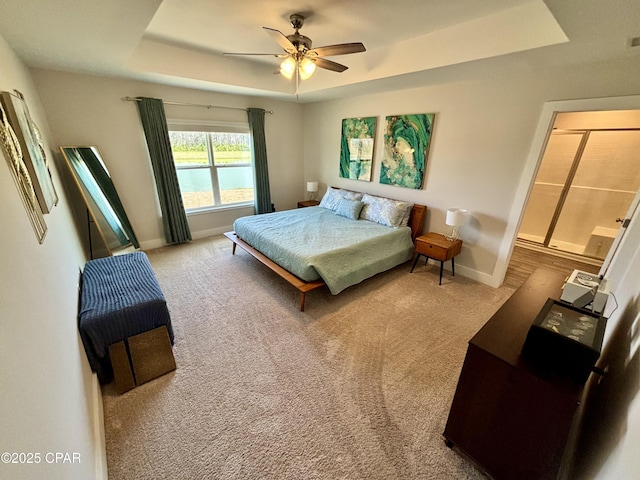 carpeted bedroom with a ceiling fan, a tray ceiling, and baseboards