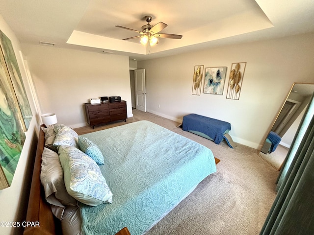 carpeted bedroom with ceiling fan, visible vents, baseboards, and a raised ceiling