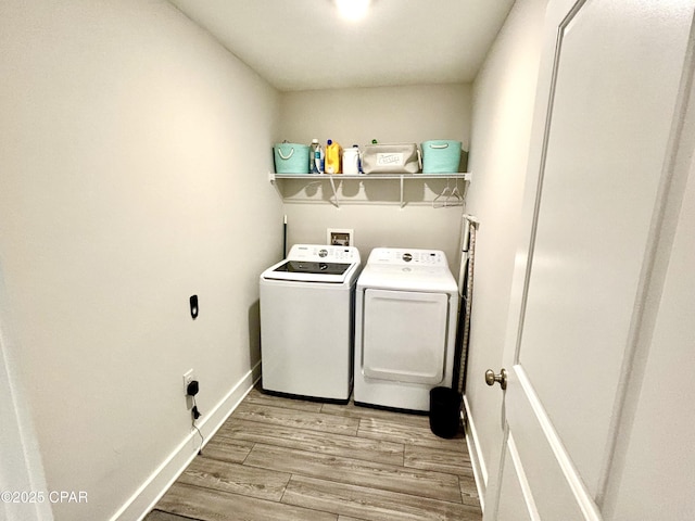 laundry area with light wood-type flooring, washer and dryer, laundry area, and baseboards