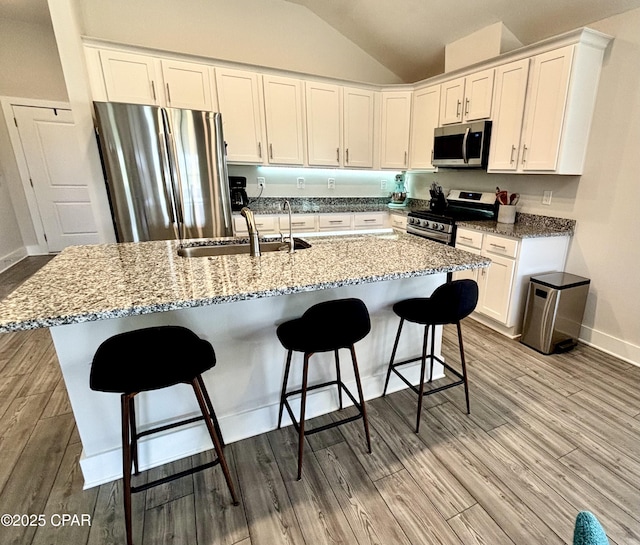 kitchen featuring stainless steel appliances, white cabinetry, a sink, and wood finished floors