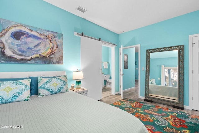 132 Gulf Terrace Ln, Port St Joe, FL 32456 - bedroom with a barn door, wood finished floors, baseboards, and ensuite bath