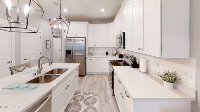 kitchen featuring stainless steel appliances, white cabinets, light countertops, and a sink