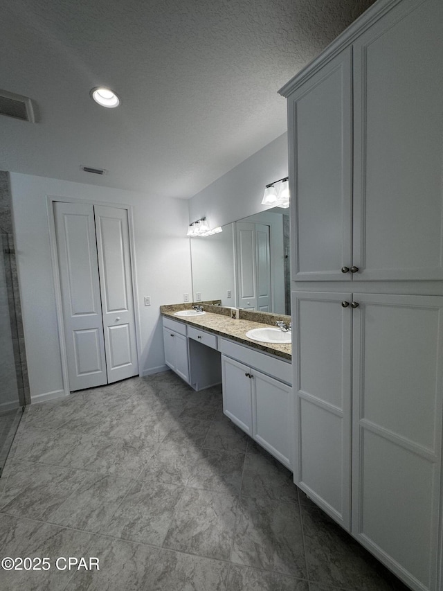 bathroom with baseboards, recessed lighting, a sink, and double vanity