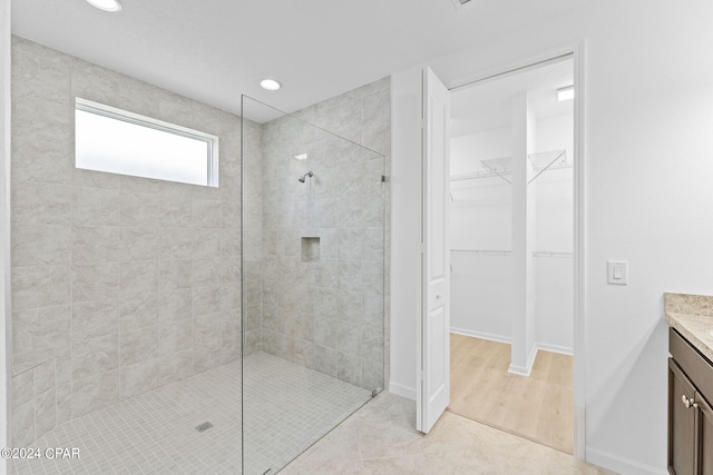 full bath featuring vanity, baseboards, recessed lighting, a walk in shower, and a walk in closet