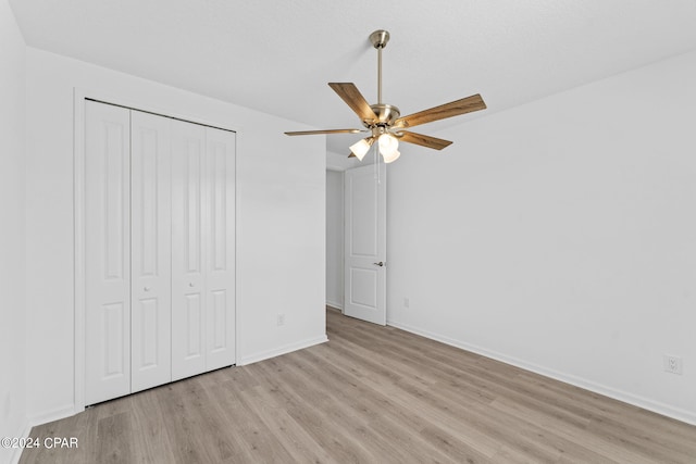 unfurnished bedroom featuring ceiling fan, a closet, light wood finished floors, and baseboards