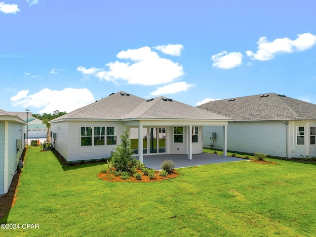 back of house featuring roof with shingles, a patio area, fence, and a lawn