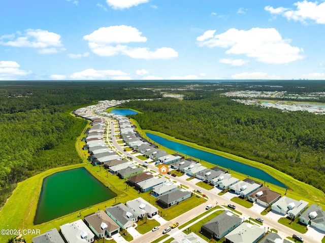 drone / aerial view featuring a wooded view, a residential view, and a water view
