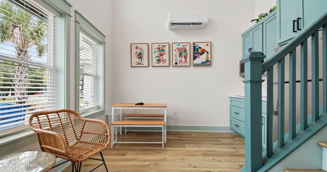 sitting room featuring light hardwood / wood-style floors and an AC wall unit