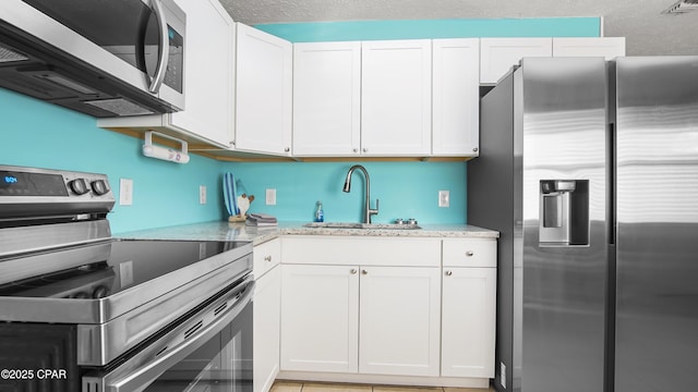 kitchen featuring sink, stainless steel appliances, white cabinetry, and light stone counters