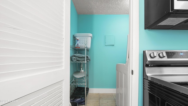 clothes washing area with a textured ceiling and light tile patterned floors