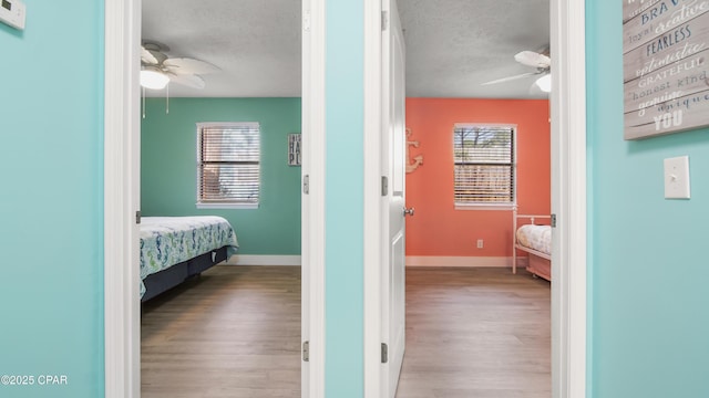 bedroom featuring light wood-type flooring, ceiling fan, and a textured ceiling