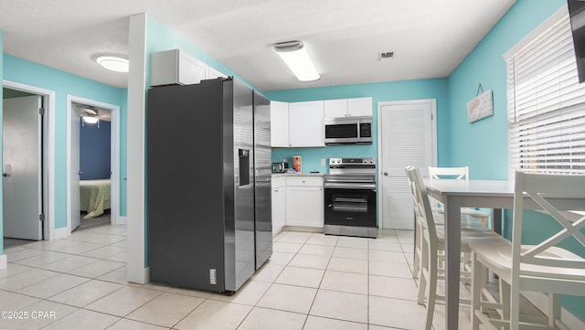 kitchen featuring a textured ceiling, white cabinetry, stainless steel appliances, and light tile patterned floors