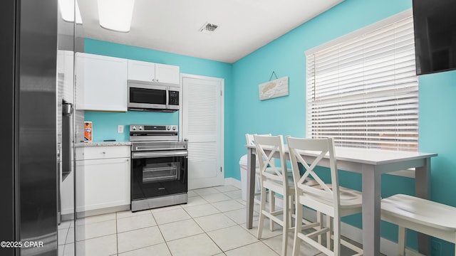 kitchen featuring white cabinets, appliances with stainless steel finishes, and light tile patterned floors