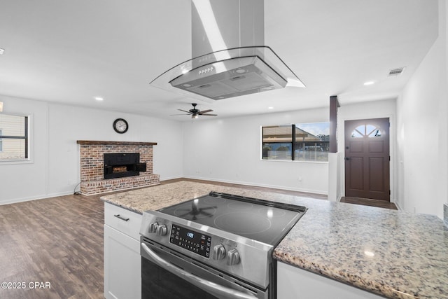 kitchen with electric stove, white cabinetry, light stone countertops, and island exhaust hood