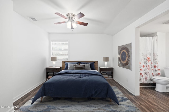 bedroom with ensuite bath, vaulted ceiling, ceiling fan, and dark hardwood / wood-style floors