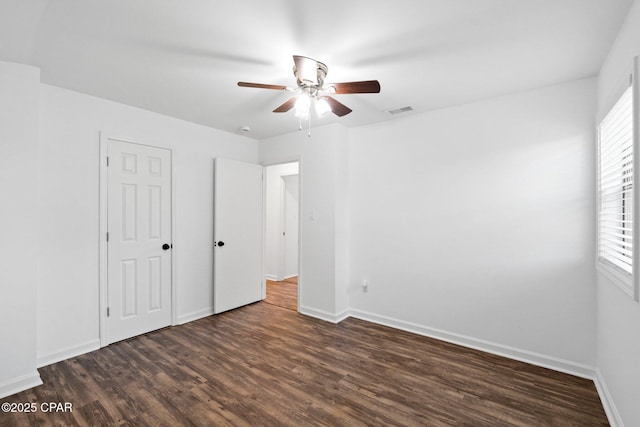 unfurnished bedroom with ceiling fan and dark wood-type flooring